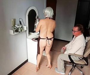 Naturist barbershop. Naked woman hairdresser in an apron